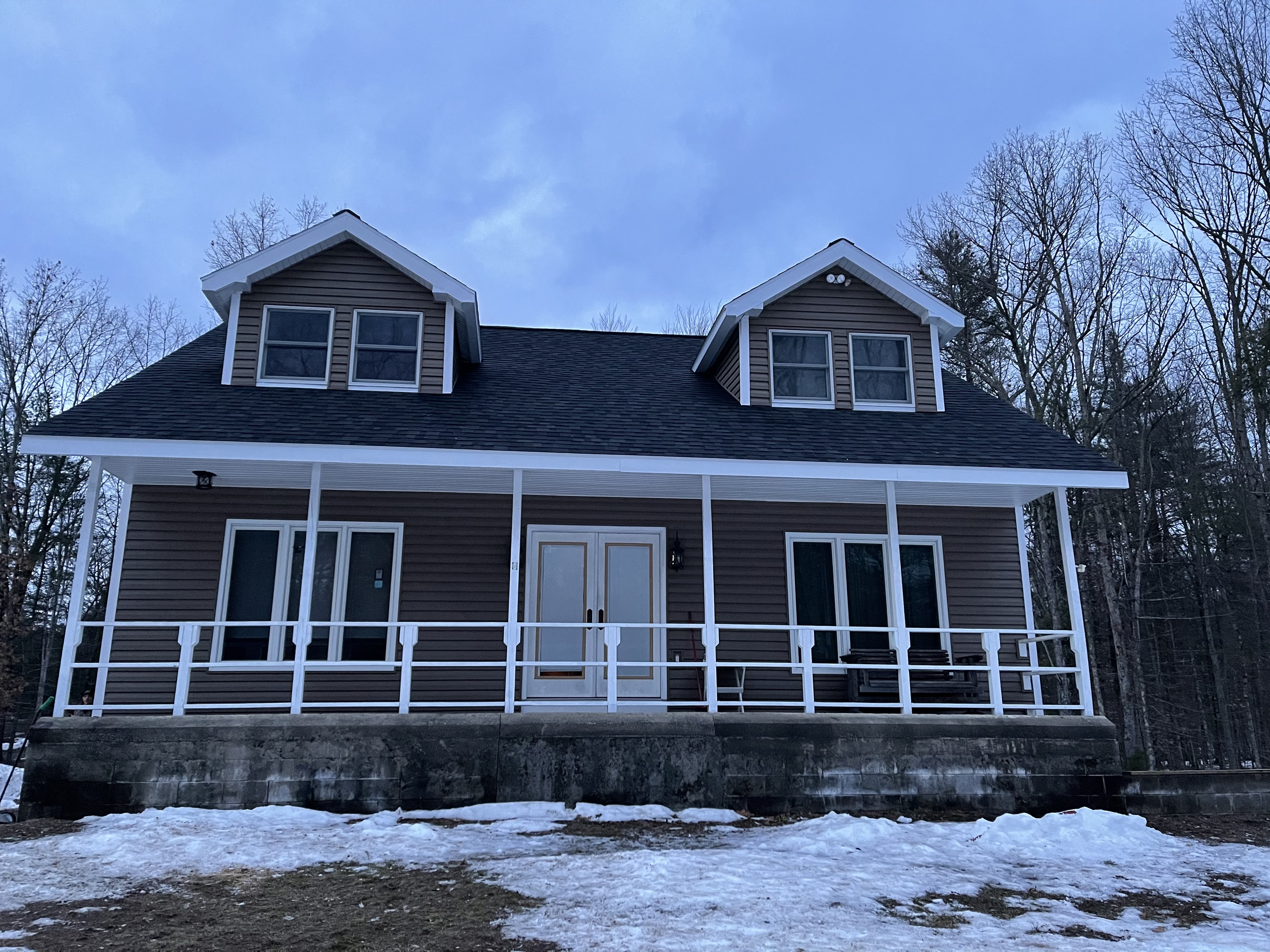 Avant Contracting - Exterior of a two-story residential home with brown siding in winter.