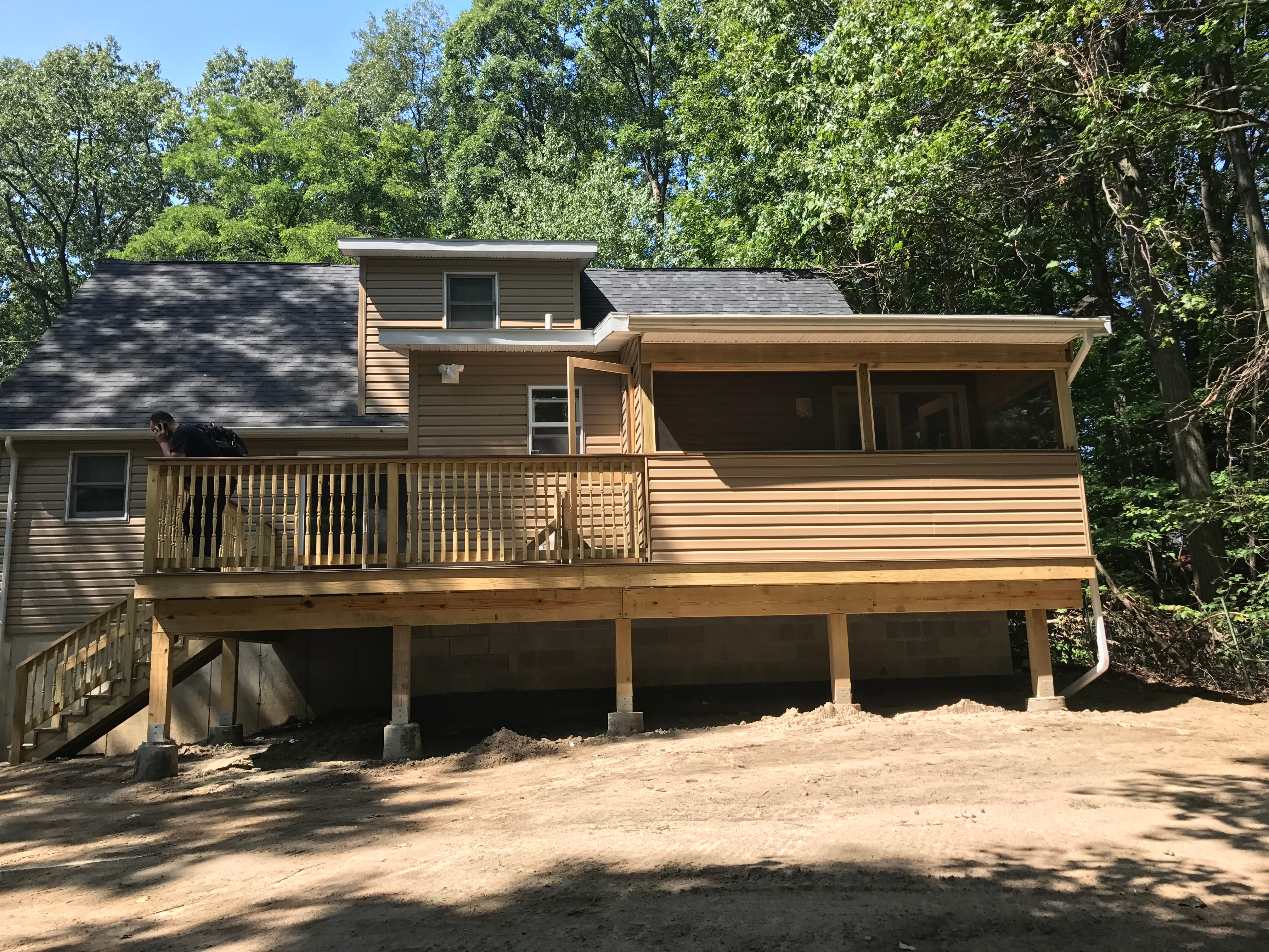 Avant Contracting - Rear of a house with a new wooden deck and screened-in porch.