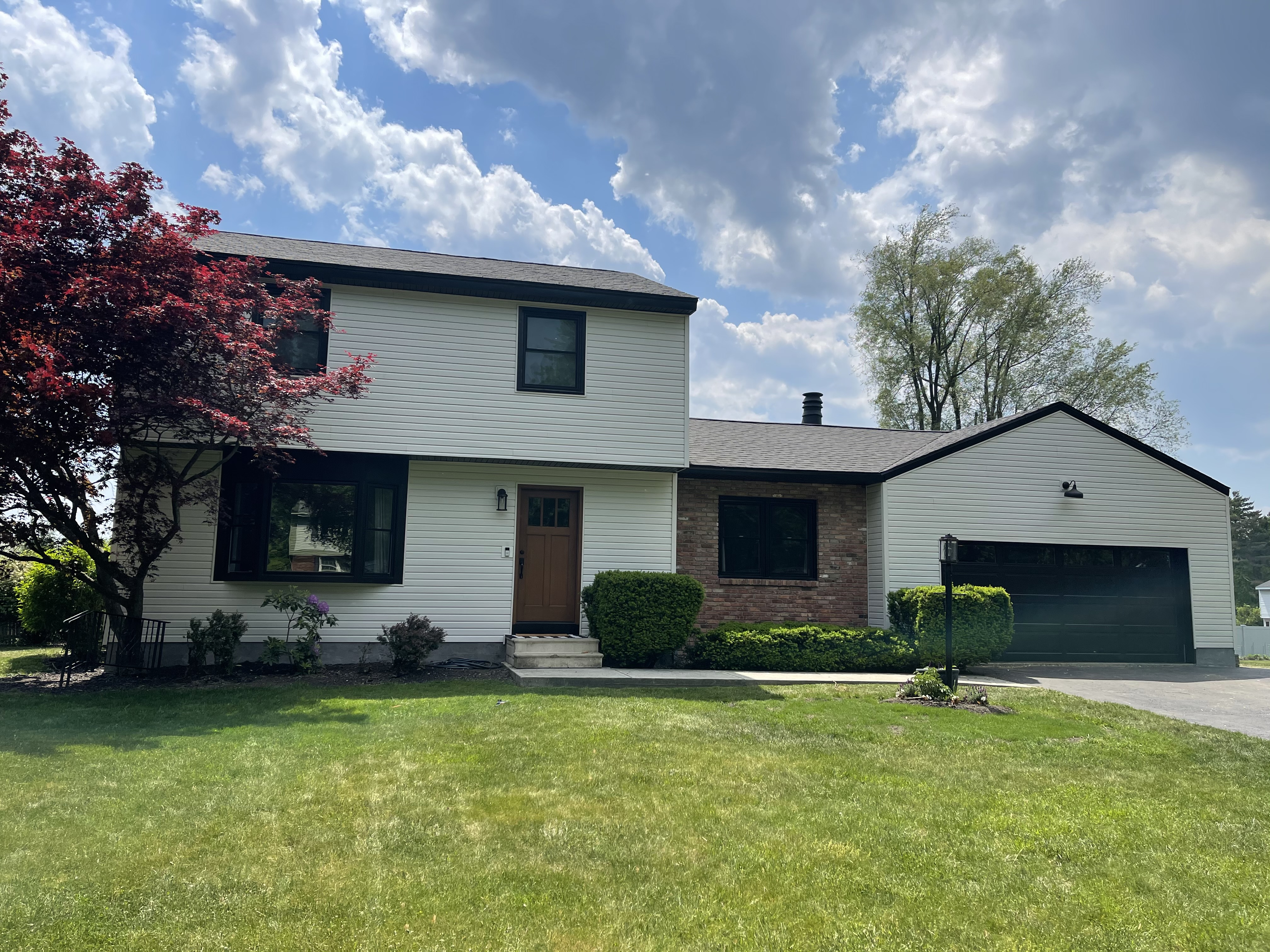 Avant Contracting - Front exterior of a residential house with white siding and green lawn.